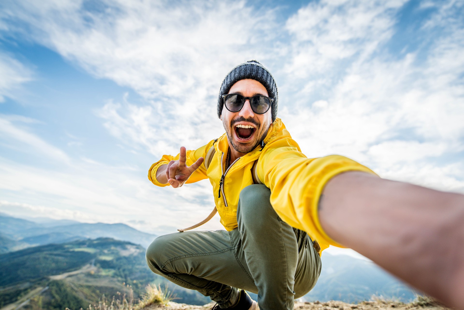 Young hiker man taking selfie portrait on the top of mountain - Happy guy smiling at camera - Hiking and climbing cliff