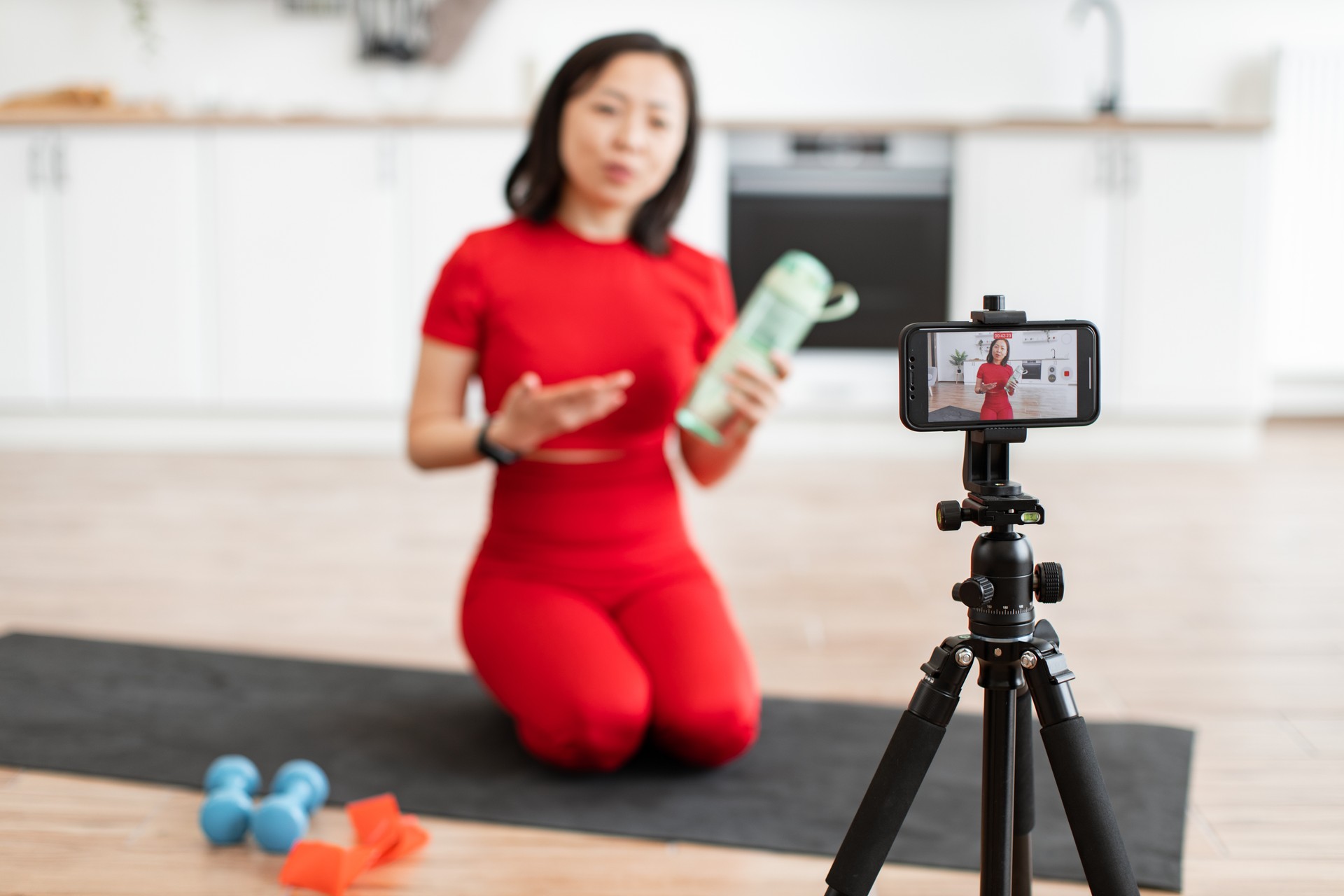 Woman recording fitness tutorial at home with smartphone